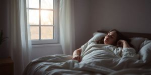 Woman peacefully sleeping in a dimly lit, comfortable bedroom.